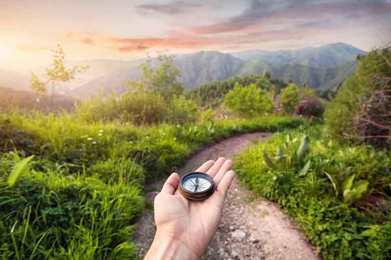hand-with-compass-at-mountain-road