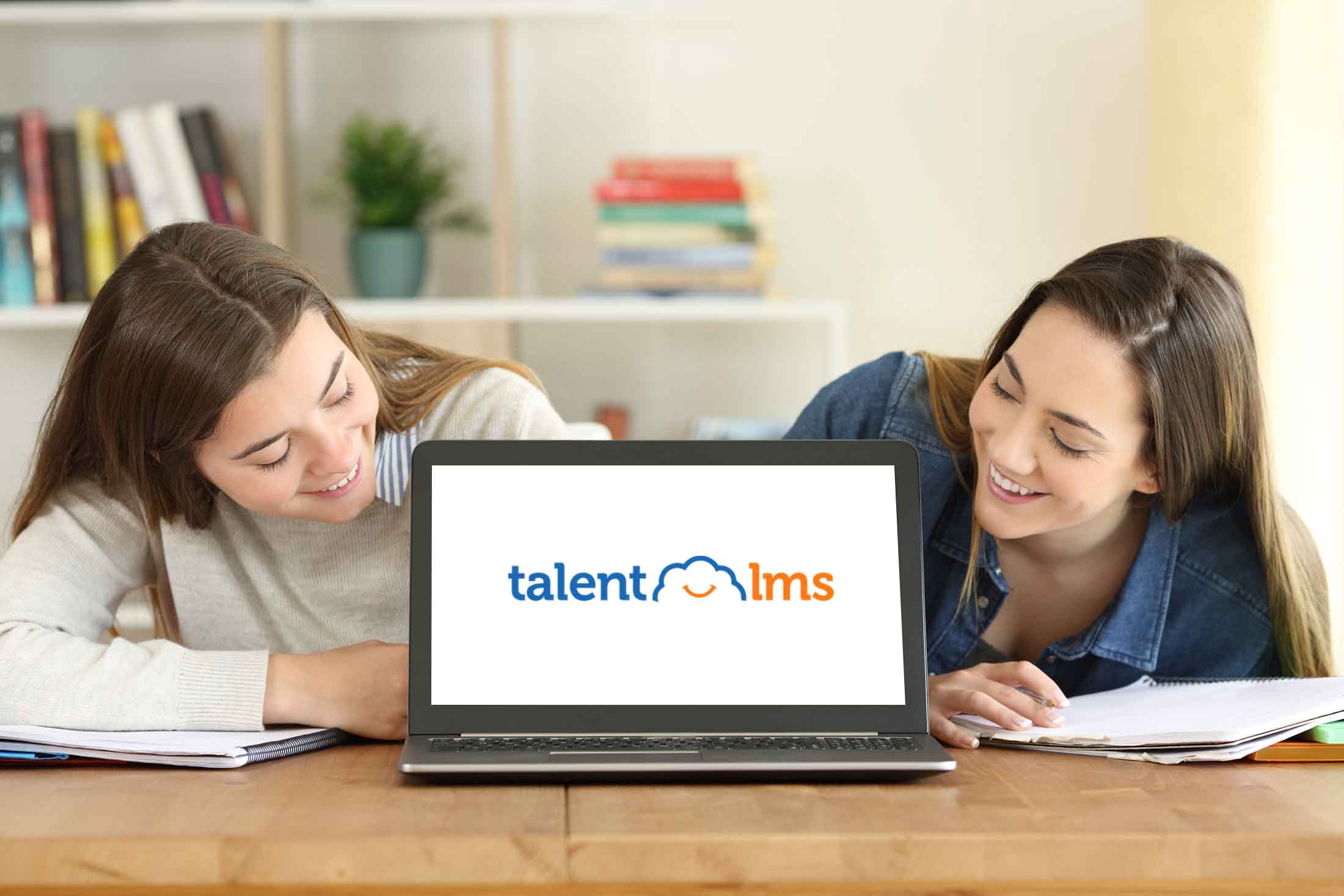 Two girls looking at a laptop set up to use TalentLMS
